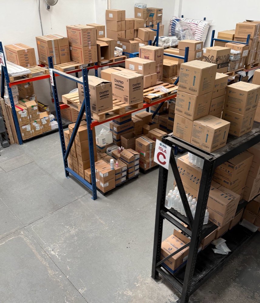 Pasillos del almacén de HMG con racks cargados de material médico e islas identificadas